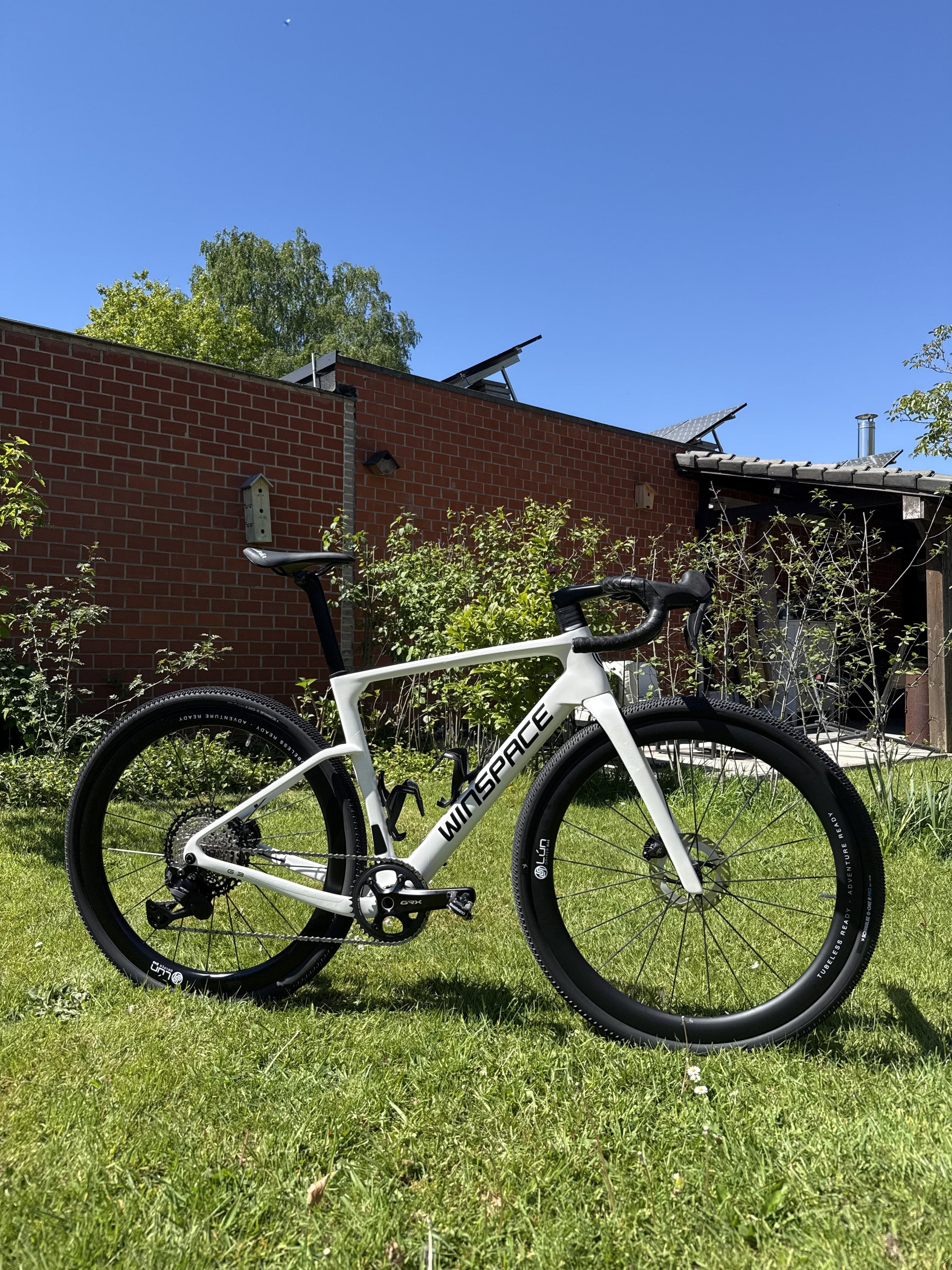 De witte Winspace G3-gravelfiets in het gras